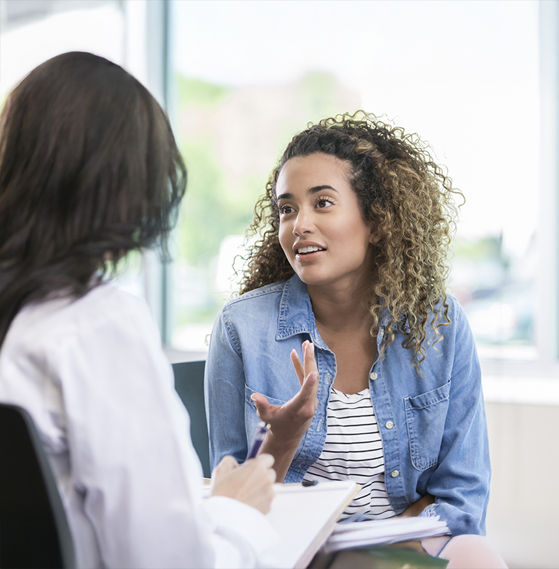 Young woman discusses symptoms with doctor